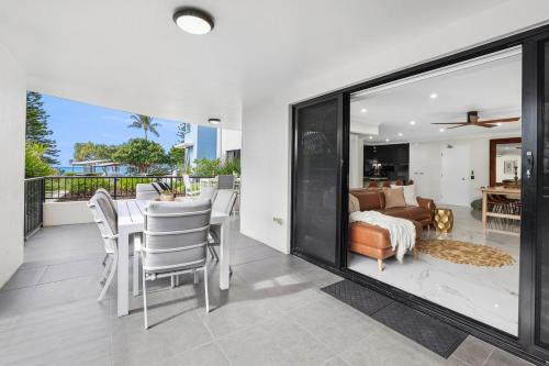 a dining room with a table and chairs and a bedroom at Oceanfront Luxe 3BR in Bargara