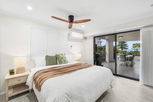 Un dormitorio blanco con una cama y un ventilador de techo. en Oceanfront Luxe 3BR, en Bargara