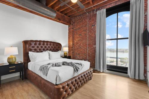 Un dormitorio con una pared de ladrillo y una cama grande en Daydreamer's Delight! River View - Walk to Arch, en Saint Louis