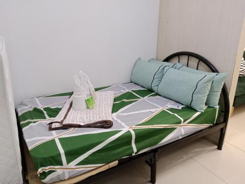Una cama con una colcha verde y blanca encima. en Sea Residence Tower A by Stave, en Manila