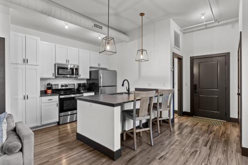 a kitchen with white cabinets and a kitchen island with chairs at Brick & Bed Riverfront Lofts, PC 203 in Saint Louis