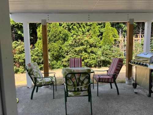 a porch with three chairs and a table and a stove at Angie house in Nanaimo