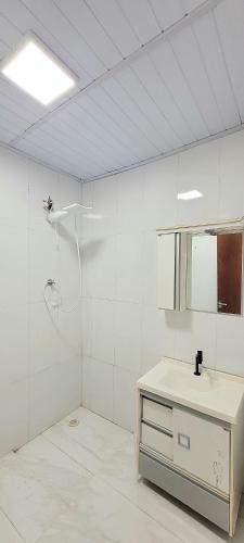 a white bathroom with a shower and a sink at Aliança da Fé in Cachoeira Paulista
