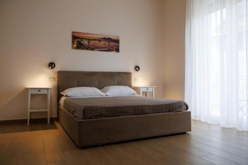 a bedroom with a bed with two night stands and two windows at Maison Marechiara in Castellammare di Stabia