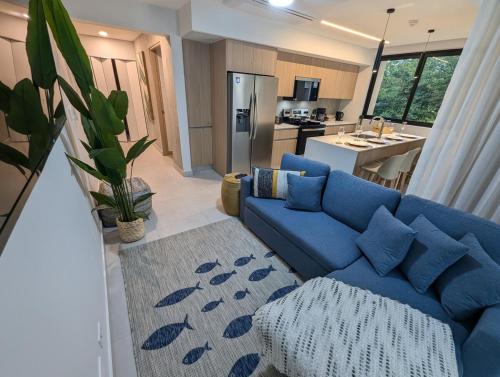 a living room with a blue couch and a kitchen at Stylish 2 bed and 2 bath condo with mountain and pool view in Jacó in Jacó