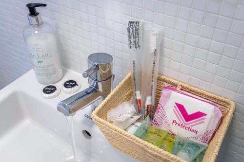 a basket on a sink with toothbrushes and a bottle of soap at Bull Ring Apartment City Views Free Parking in Birmingham
