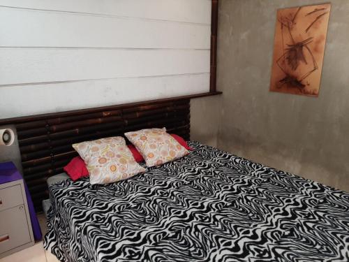 a bed with black and white sheets and two pillows at Eden river Tontouta in La Tontouta