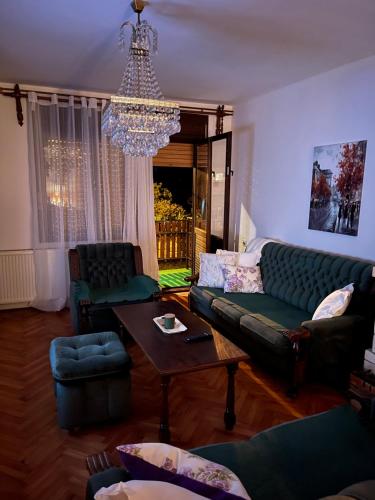a living room with a couch and chairs and a chandelier at Loza House in Arandjelovac