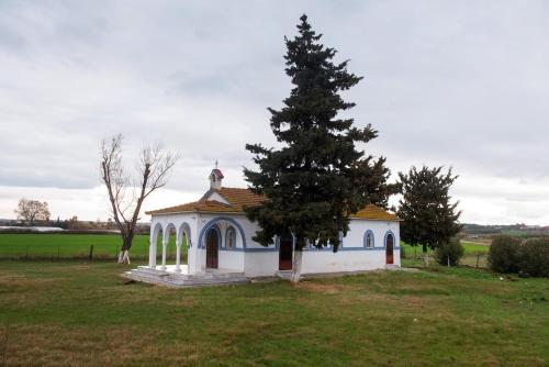 a small chapel with a tree in a field at Infinite blue Horizon Elegance Hospitality in Epanomi