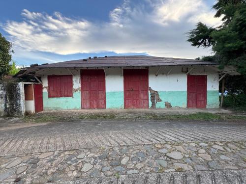 an old building with red doors and a roof at Casa en el árbol en Titiribi in Titiribí