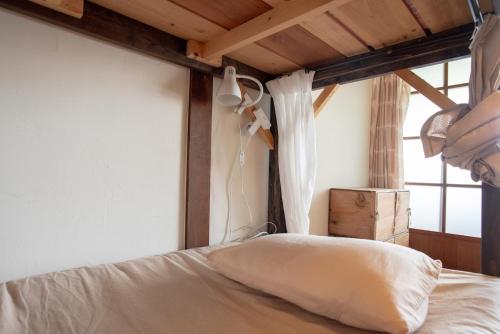 a bedroom with a white bed with a window at 伊勢ゲストハウス紬舎-Ise Guesthouse Tsumugiya- in Ise
