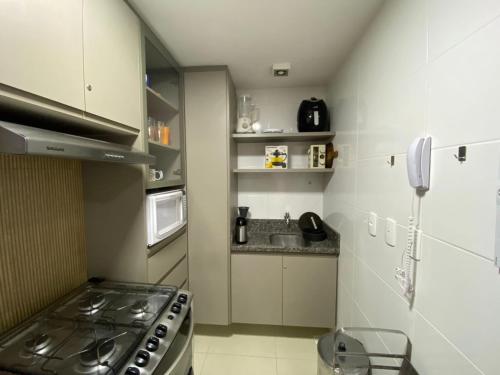 a small kitchen with a stove and a microwave at Apartamento Cobertura em Guarajuba Perto do Mar in Camaçari