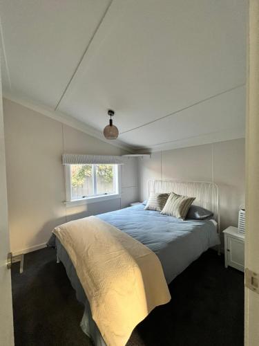 a bedroom with a bed with a blue comforter and a window at Cottage on Duke in Cambridge