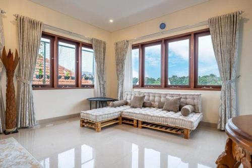a living room with a couch and large windows at Modern 5BR Luxury Villa with Pool & Rooftop - 100m from Sanur Beach in Sanur