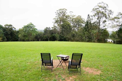 two chairs and a table in a field at Misty Mountain Retreat by Tiny Away in Peeramon