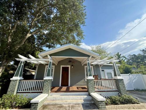 una casa pequeña con un porche delantero con una puerta en Tampa Jungalow- Pool Oasis, en Tampa