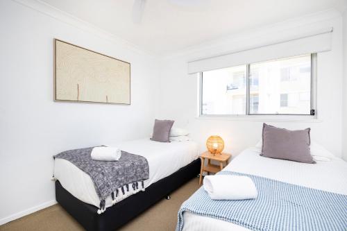 2 Betten in einem Zimmer mit weißen Wänden und Fenstern in der Unterkunft El Sandi, Unit 10, 14-18 North Street in Forster