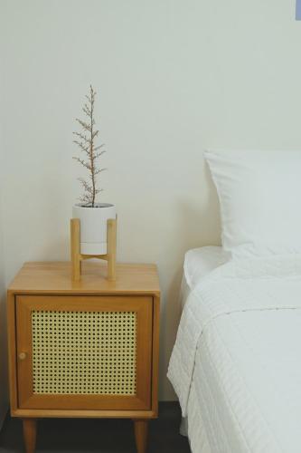a plant on a night stand next to a bed at Alto 202 in Seoul