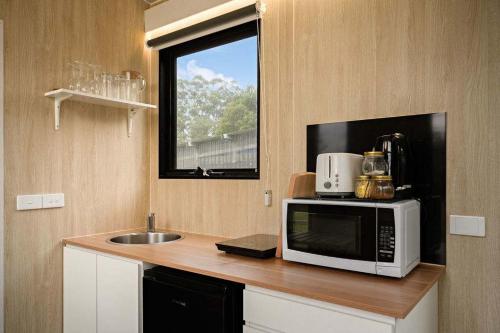 a kitchen with a microwave and a sink and a window at High on a Mountain Top by Tiny Away in Koornalla
