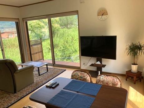 a living room with a flat screen tv and a couch at Yufuin-Sanso Waremokou in Yufuin