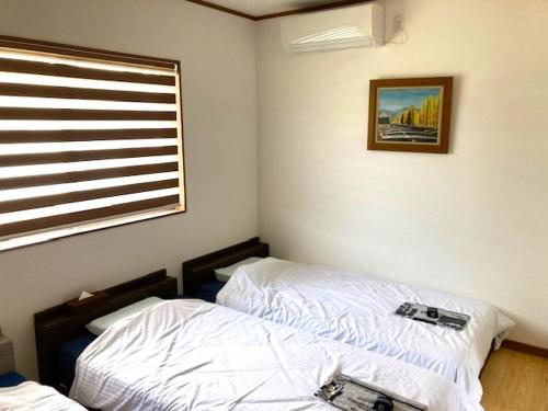 a bedroom with two beds and a window at Yufuin-Sanso Waremokou in Yufuin