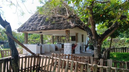 a house with a thatched roof and a wooden fence at Seasoul Sanctuary in Shimoni