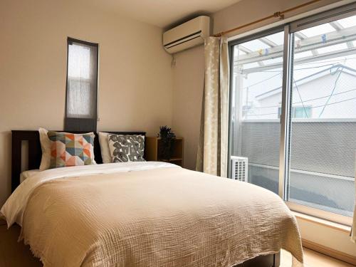 a bedroom with a bed and a large window at Arashi Kohama Direct to Namba Kohama Station 5 minutes Cozy Mansion in Wada