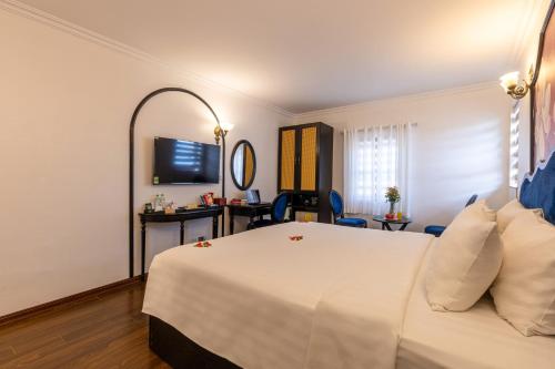a hotel room with a white bed and a mirror at Hanoi House Hotel & Travel in Hanoi