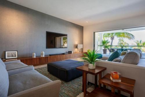 a living room with a couch and a tv at 3BR Beachfront Luxury Condo w/ Great Features in Cancún