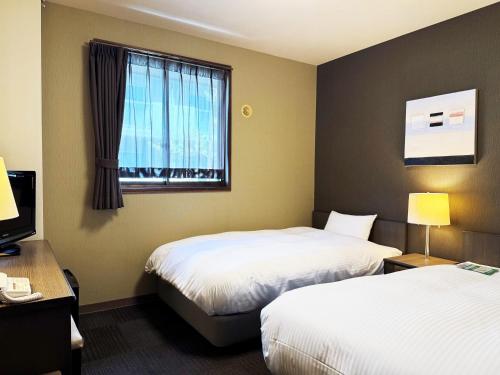 a hotel room with two beds and a window at Hotel Route-Inn Court Kashiwazaki in Kashiwazaki