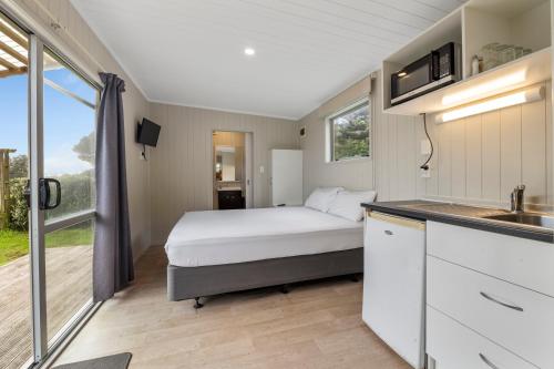 a small bedroom with a bed and a kitchen at Fitzroy Beach Holiday Park in New Plymouth