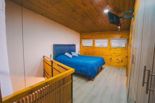 a bedroom with a blue bed in a wooden room at Casa 38 en Condominio Piscina climatizada 5 pax in Pichilemu