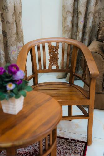a wooden chair and a table with a vase of flowers at Villa Cinta Jasmeen in Kuala Kangsar