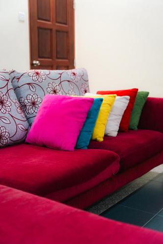 a red couch with colorful pillows on it at Villa Cinta Jasmeen in Kuala Kangsar