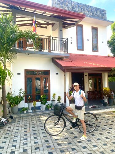 a man on a bike in front of a house at Sahan Tourist House in Polonnaruwa