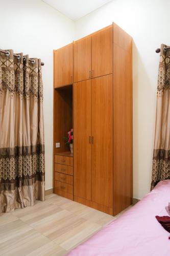 a large wooden cabinet in a bedroom with curtains at Villa Cinta Jasmeen in Kuala Kangsar