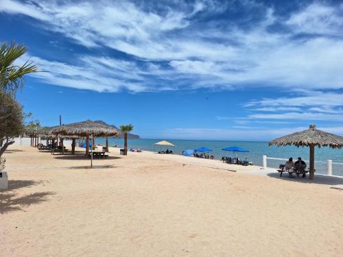 a beach with chairs and umbrellas and the ocean at #55 Suite Bungalow Seaside Hotel & Victors RV Park in San Felipe
