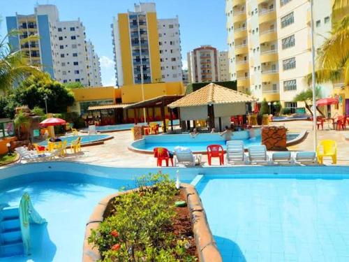 a large swimming pool with chairs and tables and buildings at Thermas Place Flat in Caldas Novas