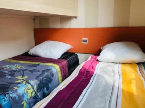 two beds sitting next to each other in a room at Mobil-home confortable avec terrasse pour 4 personnes - API-1-52-413 in Massillargues-Attuech