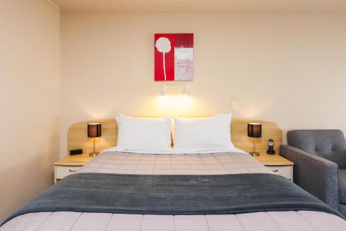 a bedroom with a bed and a chair at Braemar Motor Lodge in Palmerston North