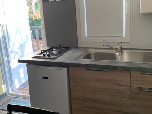 une cuisine avec un évier et une cuisinière dans l'établissement Mobil-home avec terrasse, 3 personnes, 2 chambres à Limeuil - API-1-52-454, à Limeuil