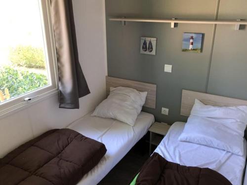 due letti in una piccola stanza con una finestra di Mobil-home 4 pers avec terrasse au camping Les Tournesols - API-1-52-489 a Crissé