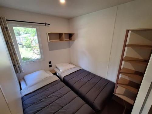 a small room with two beds and a window at Mobil-home 3 chambres avec terrasse à Valbonnais - API-1-52-473 in Valbonnais