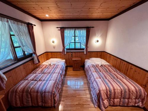 two beds in a room with two windows at Ringo Lodge Hakuba in Hakuba