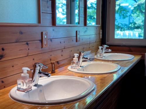 a bathroom with two sinks and two mirrors at Ringo Lodge Hakuba in Hakuba