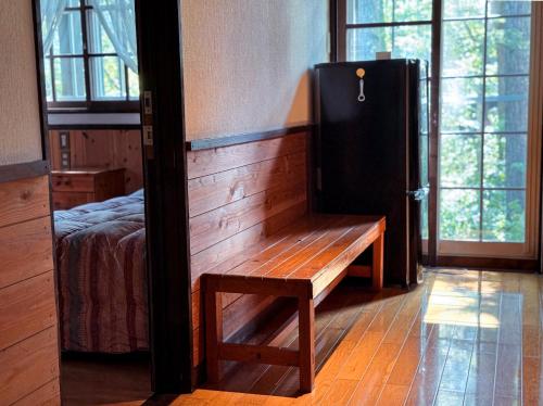 a wooden bench in a room with a bed and windows at Ringo Lodge Hakuba in Hakuba