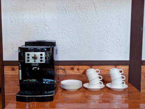 a black coffee maker with cups and saucers at Ringo Lodge Hakuba in Hakuba