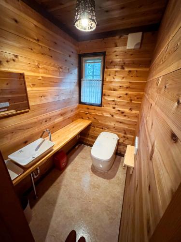 a wooden bathroom with a toilet and a sink at Ringo Lodge Hakuba in Hakuba
