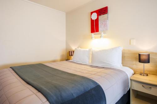 a hotel room with a bed and a table with a lamp at Braemar Motor Lodge in Palmerston North