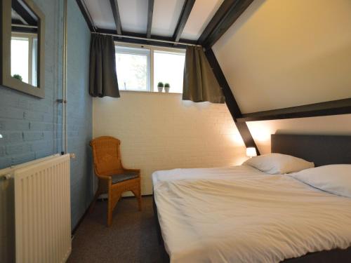 a bedroom with a bed and a chair and a window at Holiday Home in Stramproy near Nature in Stramproy